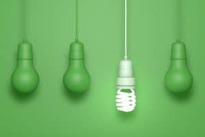 A green light bulb with four hanging bulbs against a green background, representing the benefits of smart homes.