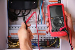 Electrician using a multimeter to troubleshoot an electrical panel, highlighting the process of diagnosing and fixing issues related to flickering lights in a household.