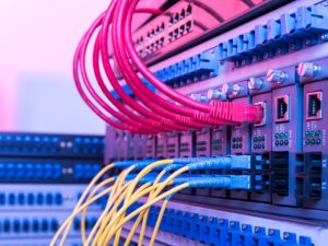 Close-up of network switches with connected yellow and red fiber optic cables, illustrating how to configure a fiber optic network.