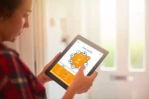 A woman using a tablet to control smart home lighting, displayed with a lighting control interface in a well-lit home.