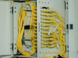 Open fiber optic terminal box displaying organized yellow cables, highlighting potential signal loss from improper connections.