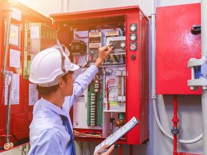 A technician inspecting a fire alarm control panel for fire alarm panel troubleshooting.