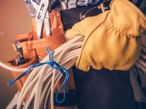 Worker with tools and cables in hand highlighting the importance of effective cable management for workplace organization.