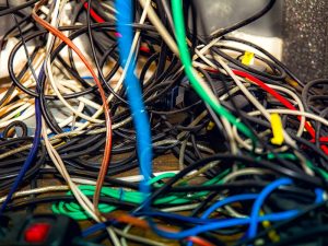 A messy bundle of tangled wires showcasing the need for cable management to improve workplace safety and efficiency.