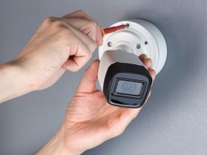 A technician installs a security camera on a wall, ensuring clear footage to prevent blurry CCTV.